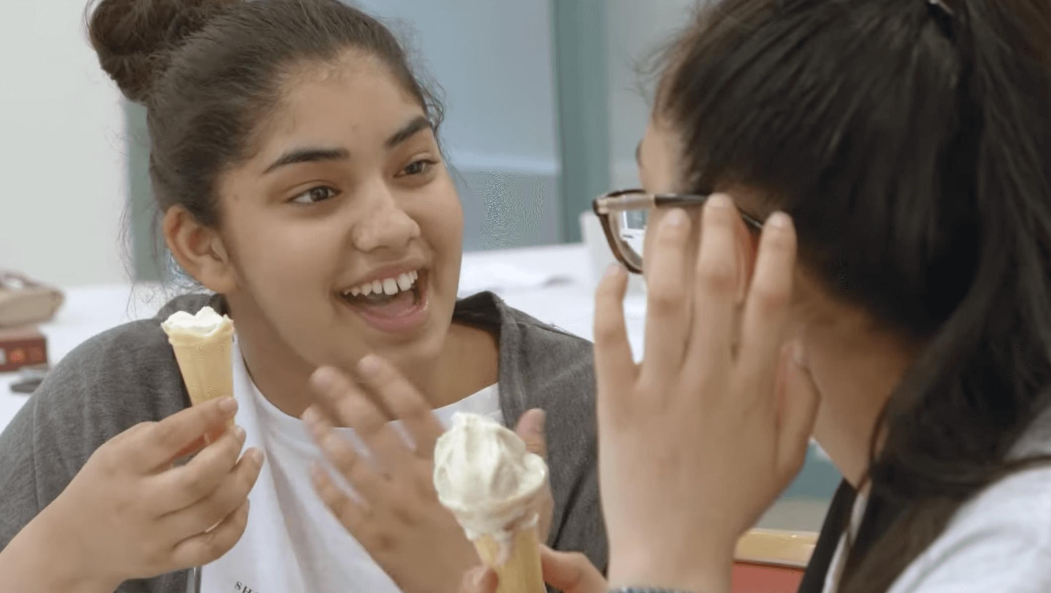 Two girls talking, one is eating ice cream